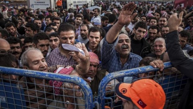 Syrian Kurdish refugees press against a gate as they hope to be allowed into Turkey.