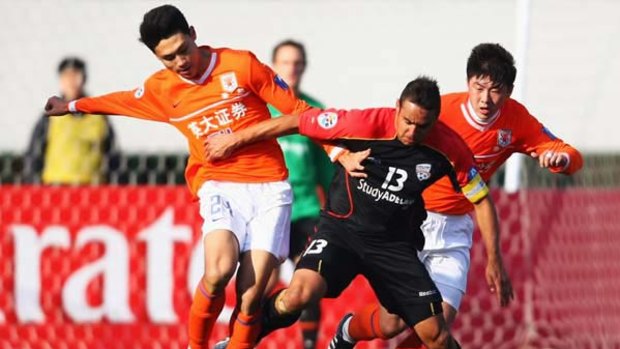 Travis Dodd, centre, of Australia's Adelaide United challenges Liu Jindong, left, of China's Shandong Luneng during the AFC Champions League match.