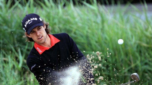 Sand storm ... Aaron Baddeley chips out of a bunker on his first round yesterday. The Australian was one over through his first seven holes.