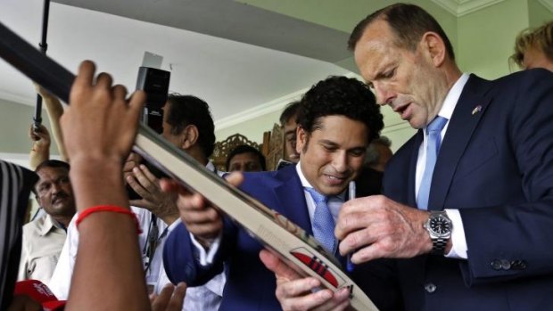 Cricket diplomacy ... Prime Minister Tony Abbott, signs a cricket bat for a youngster as India'?s retired batting maestro Sachin Tendulkar watches during the event in Mumbai, India.