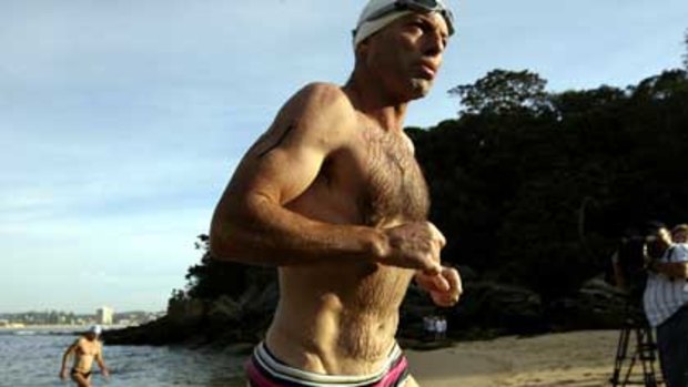 Tony Abbott strides from the surf after a charity swim near Manly.