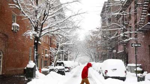 A man walks down a street following a large snowstorm in New York.