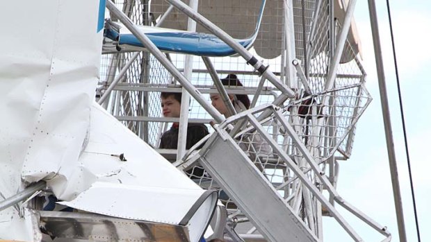 Pilot and passenger and two children await rescue after the ultra-light crashed into a ferris wheel at a country fair near Taree.