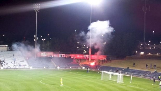 A flare is lit at Campbelltown Stadium last night.