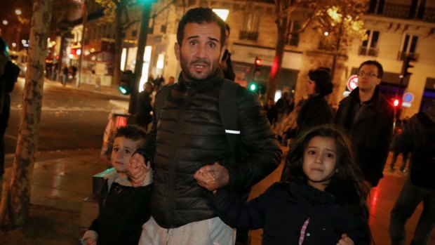 A father with his children leave Place de la Republique after crowds dispersed in a panic and police drew their weapons.