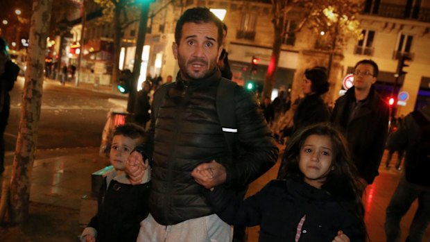 A father with his children leave Place de la Republique after crowds dispersed in a panic and police drew their weapons.