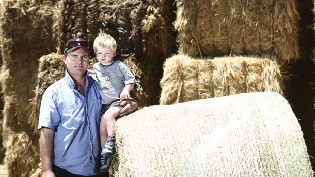 ''Someone's got to do something'': Brendan Farrell with his son Sam, 2, with donated hay at Burrumbuttock.