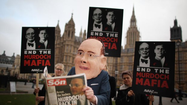A member of the Avaaz protest group poses as James Murdoch reading a spoof newspaper near Parliament in November.