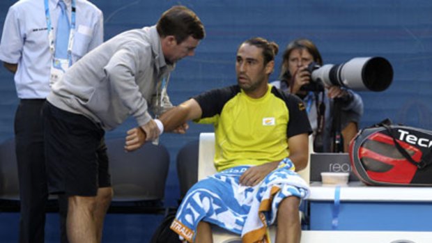Marcos Baghdatis receives medical treatment during his short-lived match against Lleyton Hewitt.