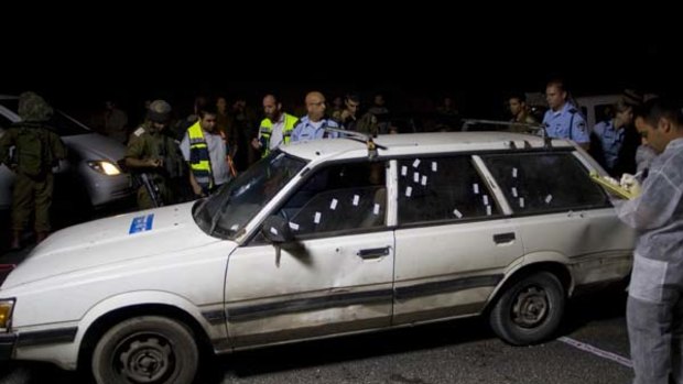Four dead ... Israeli policemen gather round the car which was shot at.