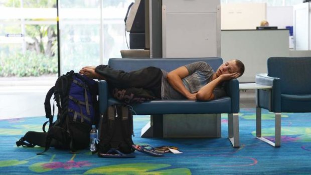 A passenger sleeps in Darwin airport on Satruday after flights were suspended due to the volcanic ash.