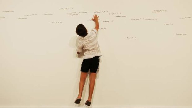 Daniel Vianello, 8, leaps up to reach higher measurements in Roman Ondak's Measuring the Universe, where visitors are asked to record their name, height and date they visited.