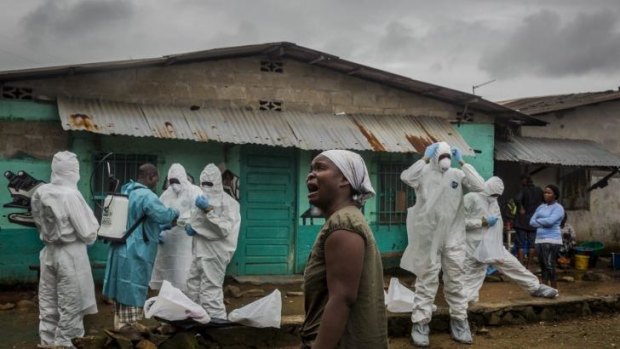 A relative grieves as a Red Cross burial team prepares to remove the body of an Ebola victim in Liberia.