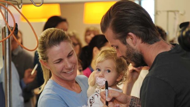 Man of the people &#8230; David Beckham signs an autograph for 19-month-old Allegra Fawson during his visit to the Royal Children's Hospital in Melbourne with the Los Angeles Galaxy team.