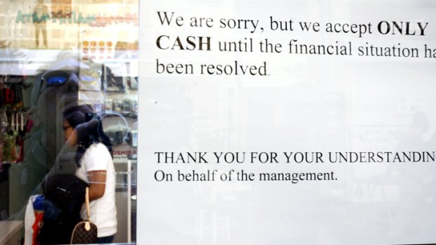 Warning signal ... A sign hangs in a window of a store in Cyprus informing shoppers that cash will only be accepted.