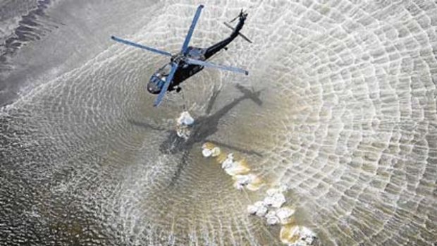 National Guard helicopters drop sand bags in a breach in the beach just west of Grand Isle, Lousiana.