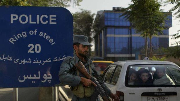 Nervous watch ...  a car full of children passes heavily armed police officers guarding Kabul’s so-called ring of steel, which has  failed to protect people from insurgents.