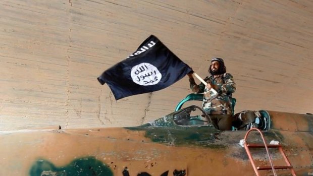 An Islamic State fighter waves the militant group's flag at the Tabqa airbase in Raqqa.