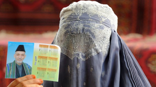 A burqa-clad female supporter of Hamid Karzai shows his picture in a calendar.
