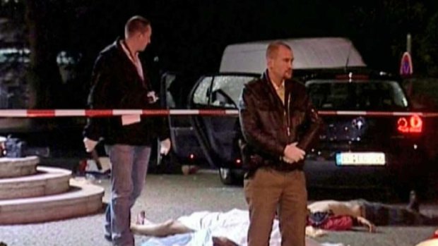 A CSI member and a policeman gather next to two bodies after six people were found dead on Wednesday morning in downtown Duisburg, western Germany, in this file picture from August 15, 2007.