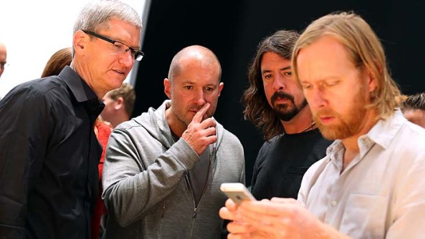 Apple CEO Tim Cook, left, Apple senior vice president of Industrial Design, Jonathan Ive, centre, and Dave Grohl of the Foo Fighters look on as Foo Fighters bass player Nate Mendel looks at the iPhone 5.