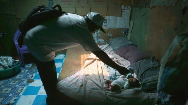 Ebola tracing coordinator John Mbayoh checks a baby's  temperature in Monrovia.