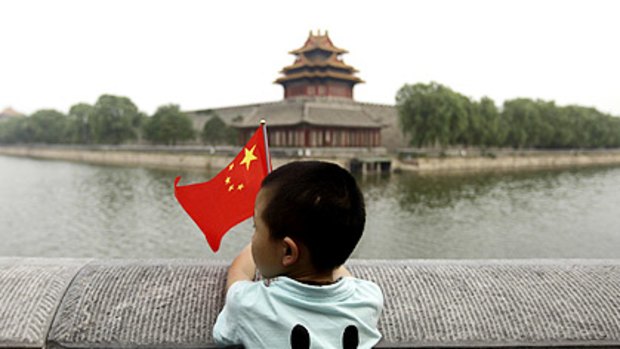 A boy holding a Chinese national flag stands outside the Forbidden City in Beijing.