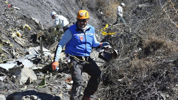 Recovery operation: A French gendarme makes his way through debris of Flight 4U 9525 in the French Alps.