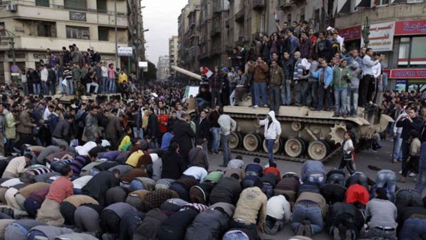 Anti-government protesters pray in front of an Egyptian army tank during a protest in Tahrir Square in Cairo.