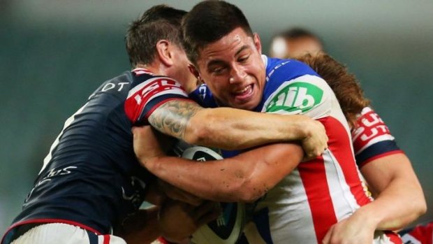 Newcastle's Joseph Tapine is well held by the Roosters' defence.