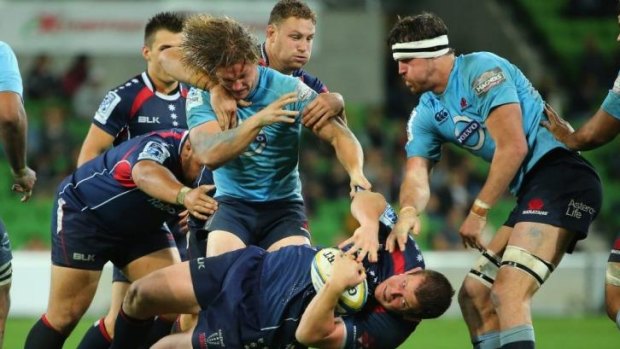 Turfed: Toby Smith of the Rebels feels the wrath of the Waratahs defence.