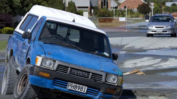 A car is trapped in the middle of the road in a sink hole caused by liquefaction in Parklands.