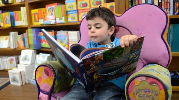 Tactile: Four-year-old Jonathan loves to cuddle up with a big picture book in his favourite reading chair at Carlton's The Little Bookroom.