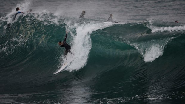 A surfer riding a large wave during a big swell off Cronulla Point in Sydney.