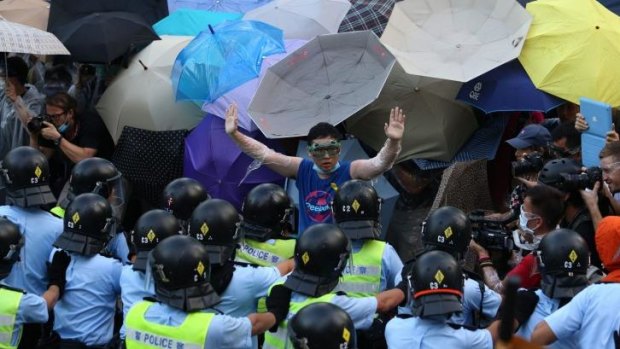 Defiant stand: A pro-democracy demonstrator gestures in front of police near the Hong Kong government headquarters.