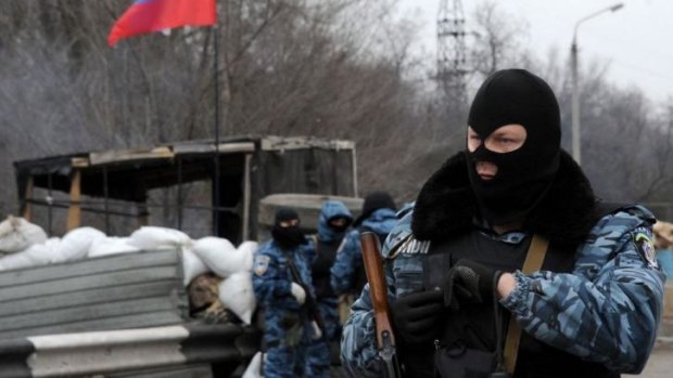 Armed masked men stand at their checkpoint under a Russian flag on a highway that connects the Black Sea Crimea peninsula to mainland Ukraine near the city of Armyansk.