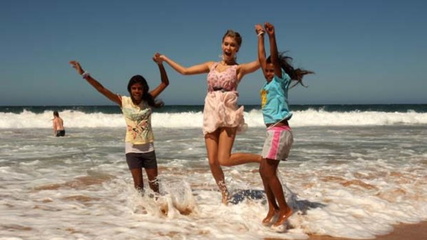 Miss World Alexandria Mills frolics in the waves with two indigenous children at South Narrabeen Surf Lifesaving Club.