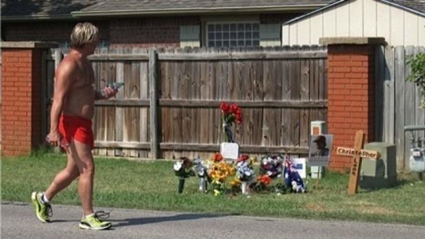 A jogger goes by the roadside memorial to Australian Chris Lane on Country Club Road in Duncan, Oklahoma.