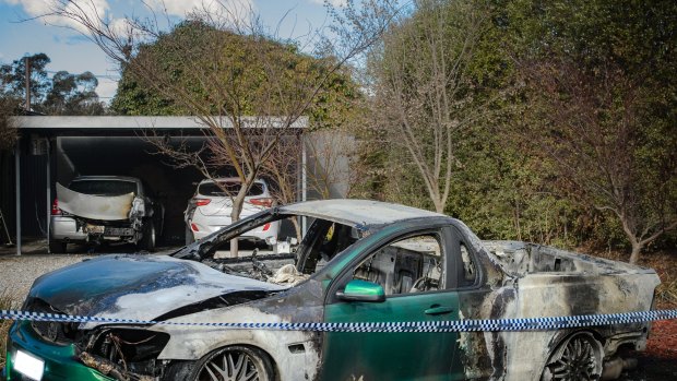 Police examine a property in Kambah after shots were fired and three vehicles were torched in July.
