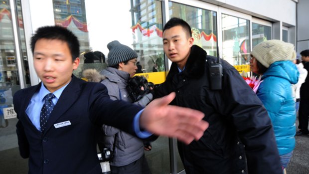 Cyber attack ... guards try to remove journalists as a woman delivers flowers to the Google office in Beijing.