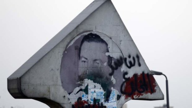 A defaced picture of former Egyptian President Hosni Mubarak with graffiti that reads, "Corrupt and deposed" along a highway in Cairo.