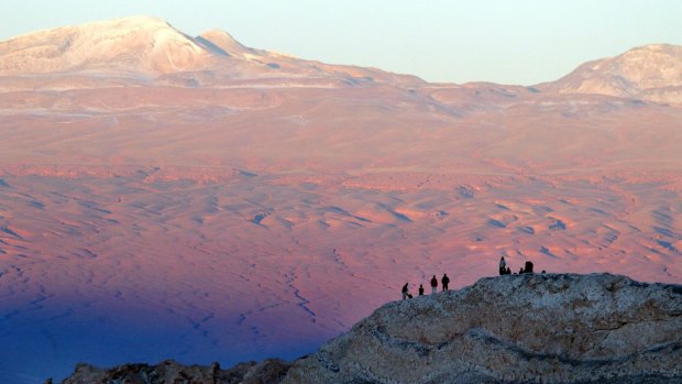 Tourists rest above a hill in Valle de la Luna (Moon Valley) in the nature reserve of Los Flamencos in the Atacama Desert. 