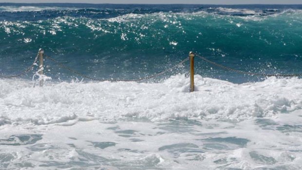 A lone swimmer does laps despite the huge waves crashing into Wylie's Baths at Coogee.