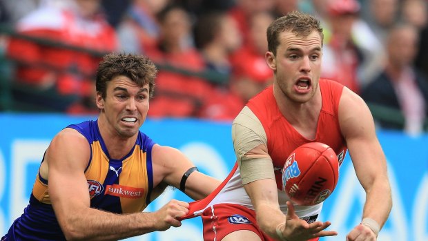 Getting away: Swan Tom Mitchell shoots a handball as he's tackled by an Eagle opponent.