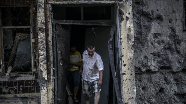 People emerge from their houses after shelling in Donetsk.