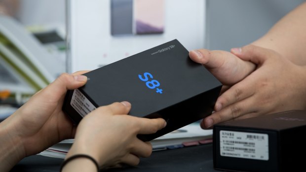 An employee hands a box containing a Samsung Electronics Co. Galaxy S8+ smartphone to a customer at KT Corp.'s Olleh Square flagship store in Seoul, South Korea, on Friday, April 21, 2017. Samsung's latest marquee device, the?S8, began shipping this week. Photographer: SeongJoon Cho/Bloomberg