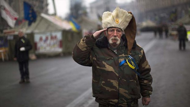 An anti-Yanukovych protester salutes as the Ukrainian national anthem is played at Kiev's Independence Square.
