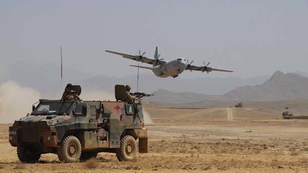 An Australian Bushmaster provides protection for an Australian C-130J that delivers vital stores and equipment to the Reconstruction Task Force troops in Southern Afghanistan.