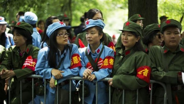 Volunteers in Chinese Red Army-style uniforms wait to meet Chen Guangbiao.