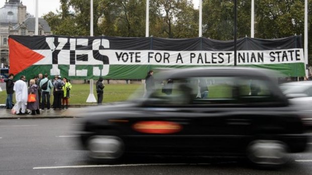 Support: A London taxi drives by as pro-Palestinian supporters position a giant banner calling for a recognised Palestinian state.